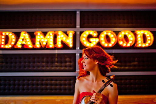 Chloé Trevor Woodard with violin beside a marquee sign